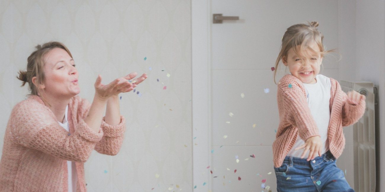 woman and child wearing beige sweater playing with confetti